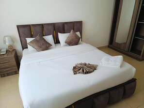 A neatly made bed with a headboard, pillows, and a folded towel. - El RAYYAN HOTEL (Amman)