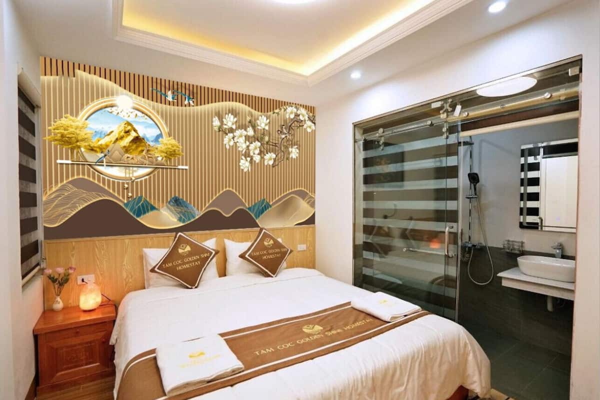 Ein Hotelzimmer mit Bett, Nachttisch, einer Wand mit Dekoration, Duschbereich und Badezimmer.