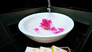 A white basin with pink flowers and a faucet, surrounded by a black tiled floor. - Tamcoc Golden Shine Homestay (Nam Hoa Lu)