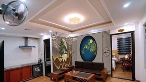 A modern living room with a sofa, coffee table, and a decorative wall mural. - Tamcoc Golden Shine Homestay (Nam Hoa Lu)