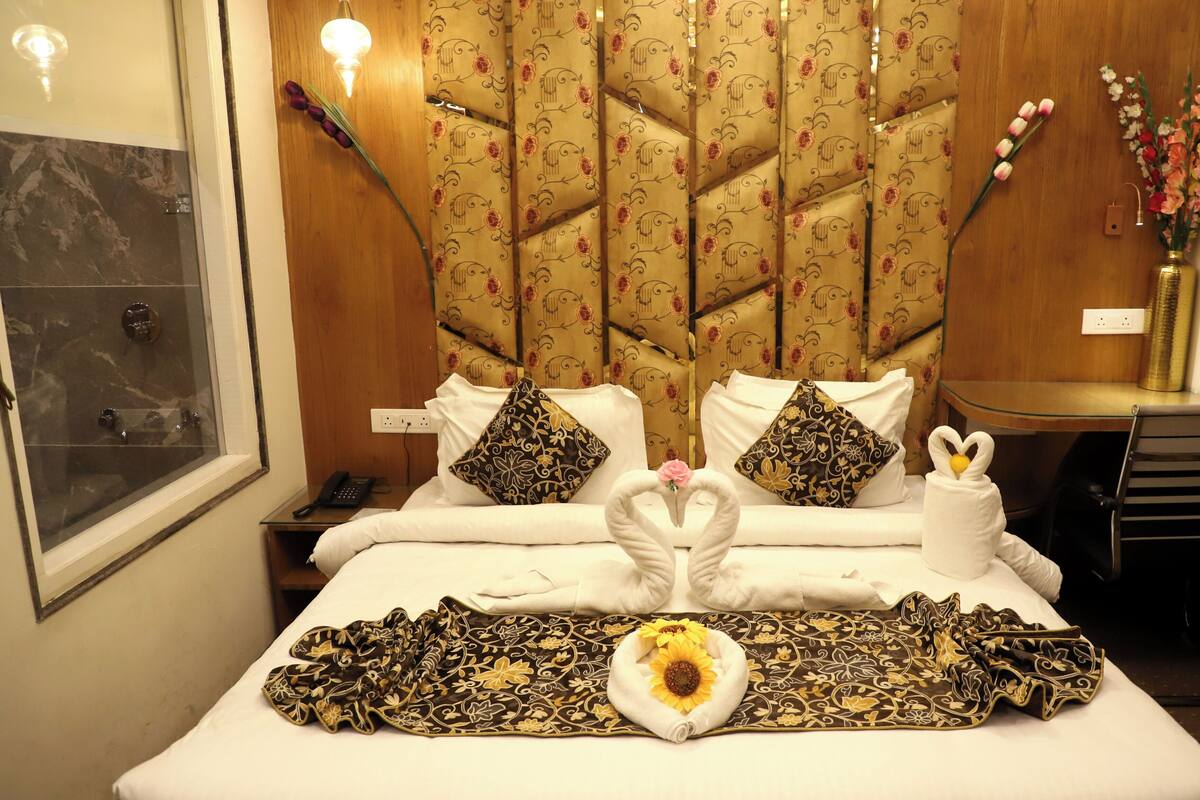 Quarto de hotel com uma cama, mesa de cabeceira, escrivaninha e uma cadeira.