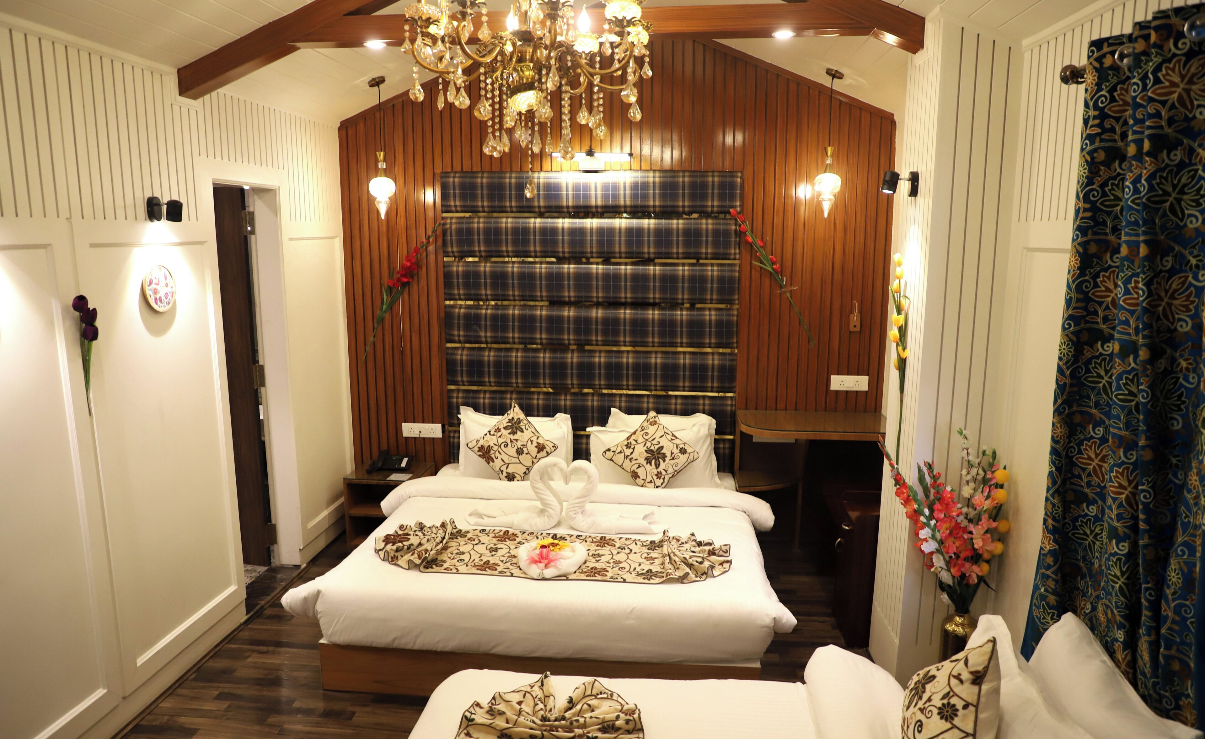 Una habitación de hotel con una cama grande, una araña, paneles de madera y un cabecero escocés.