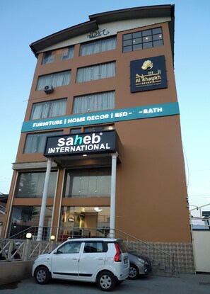 A multi-story building with signage for 'Furniture | Home Decor | Bed | Bath' and 'Saheb International.' - The Hoften Al Shaykh Resorts, Srinagar (Srinagar)