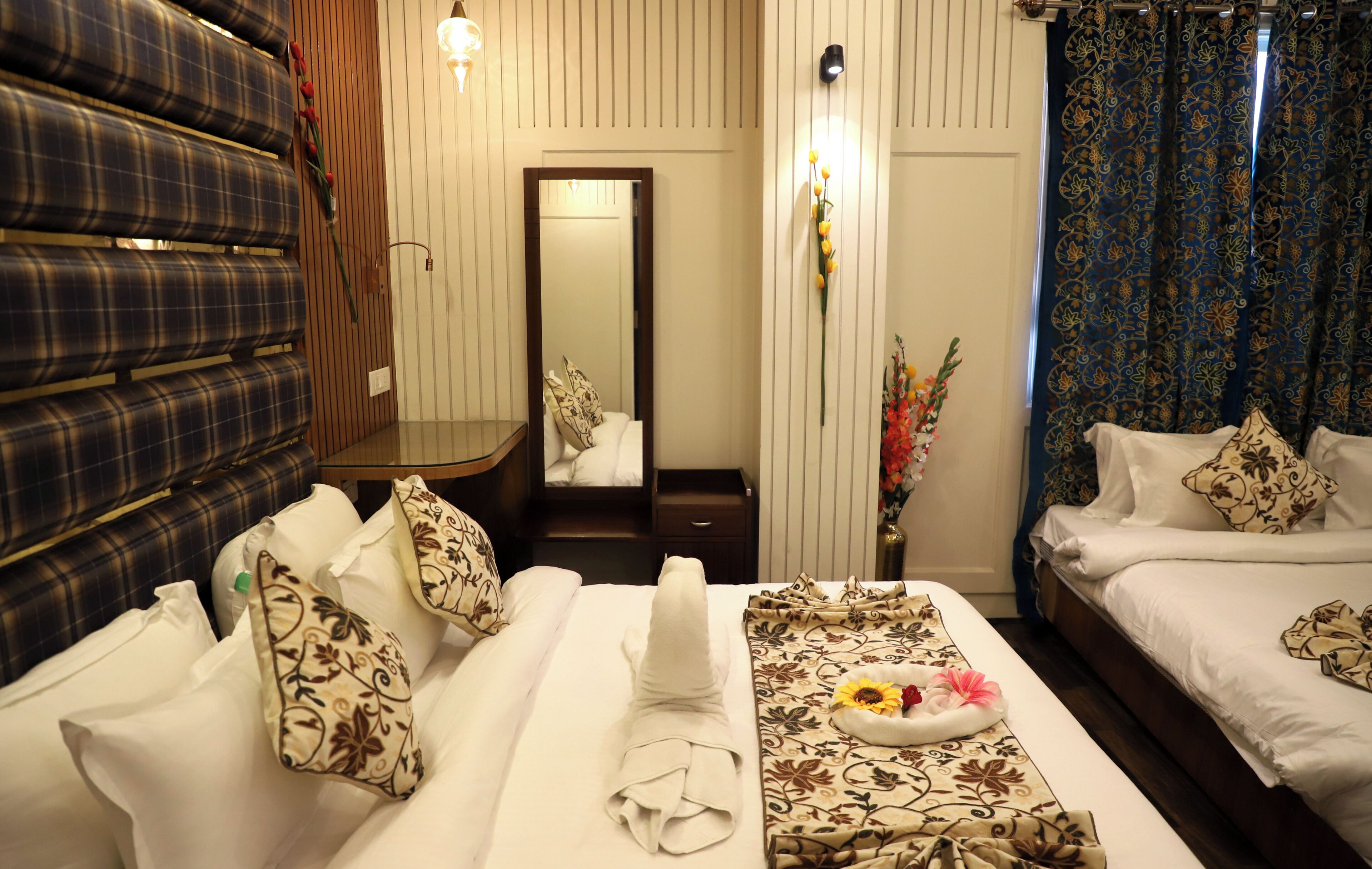 A hotel room with a bed, a sofa, a mirror, and a small table with a flower arrangement.
