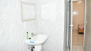 A bathroom with a white sink, a framed mirror, and a door leading to a bedroom with a bed. - Socogim ps 41 (Nouakchott Ouest)