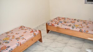 Two wooden beds with floral bedding in a room with white walls and marble flooring. - Socogim ps 41 (Nouakchott Ouest)