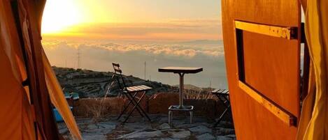 A tent with a view of a stone patio, a table, and chairs.