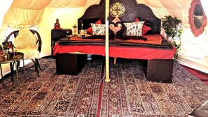 Ein Zelt mit einem Bett, einem Stuhl, einem kleinen Tisch und einem Spiegel.