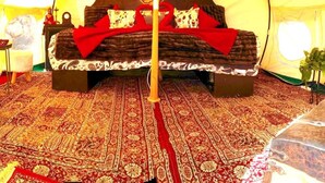 Ein Zelt mit einem Bett, einem Nachttisch und einer Lampe.