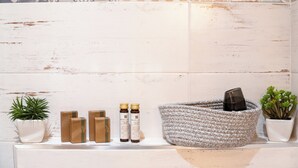 A bathroom with a white tiled wall, a woven basket, and potted plants. - The Railway 74 (La Spezia)