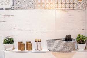 Un baño con pared de azulejos blancos, una cesta de mimbre y plantas en macetas.