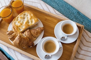Una bandeja con croissants, dos tazas de café y dos vasos de zumo de naranja.
