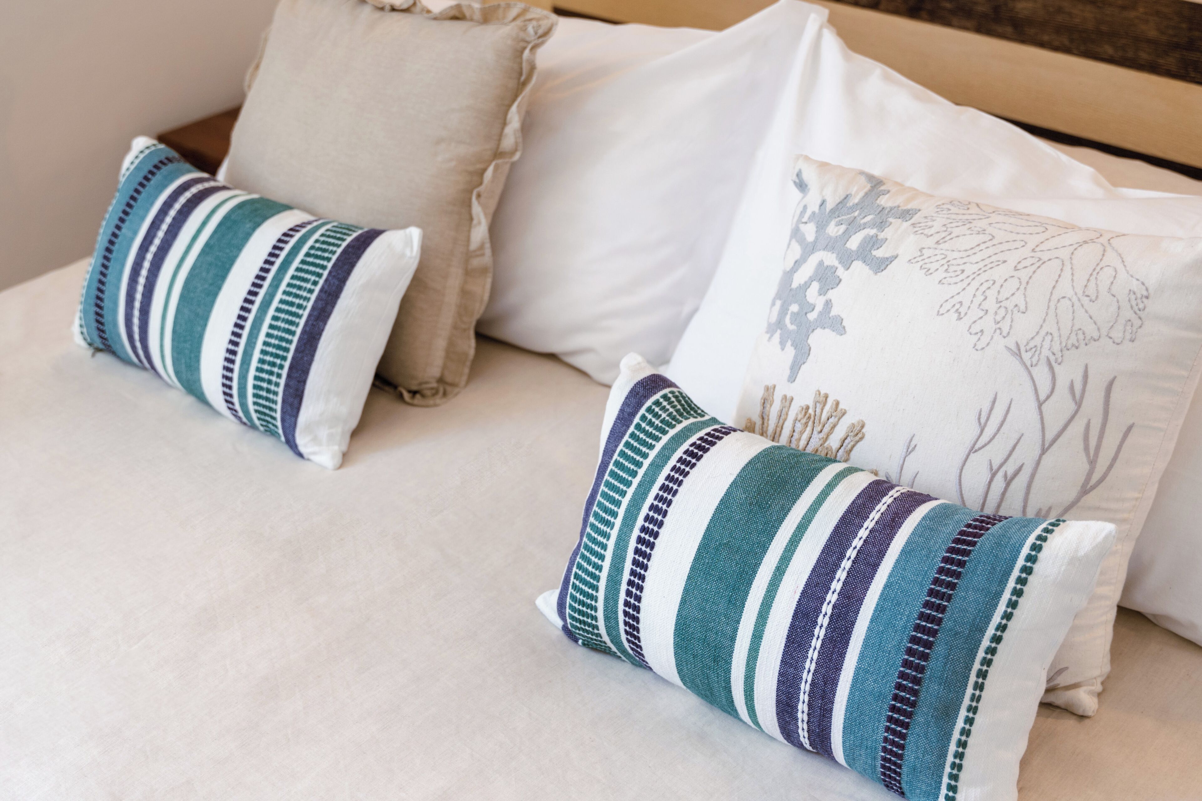 A bed with two pillows, one striped and one with a leaf pattern.