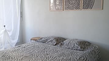 Une chambre à coucher avec une couvre-lit à motifs zébrés, une petite table de chevet en bois et trois panneaux décoratifs fixés au mur.