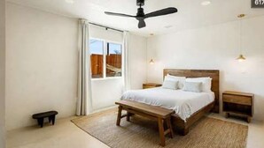 A bedroom with a bed, bedside tables, a bench, a ceiling fan, and a view through a window. - Cozy 2-bedroom Retreat in Joshua Tree (Joshua Tree)