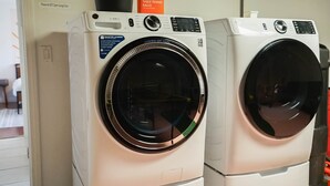 Kaksi etukuormitettavaa pesukonetta, joissa on ohjauspaneeli, etiketti, jossa lukee ”Pöytätennispallot”, ja tarra, jossa lukee ”Älykkäämpi pyykinpesu”.