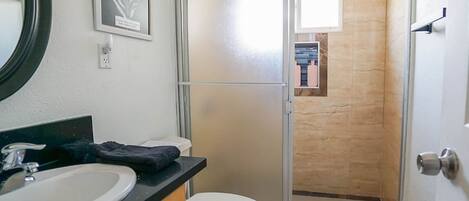 A bathroom with a sink, toilet, and a glass shower door.
