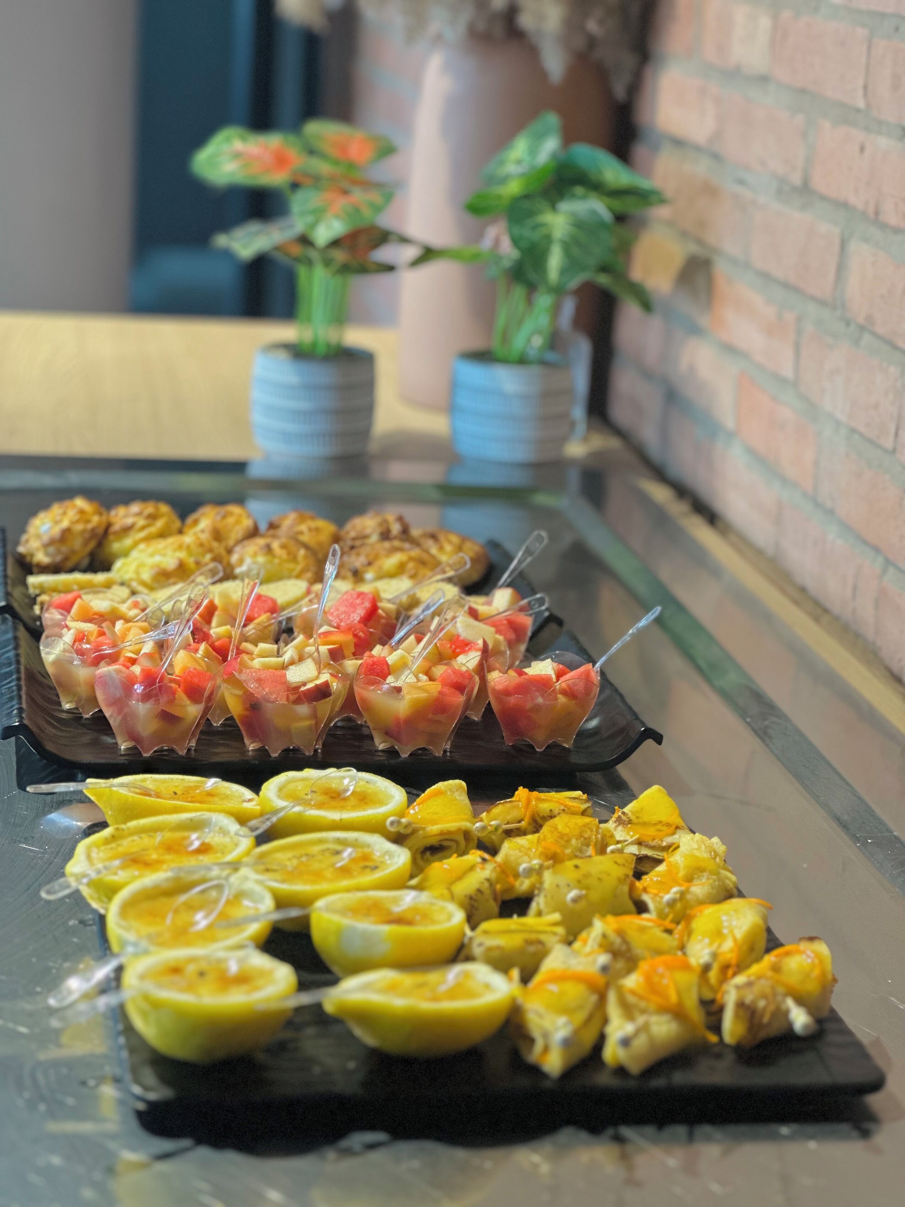 A buffet with various food items including fruit skewers and pastries.