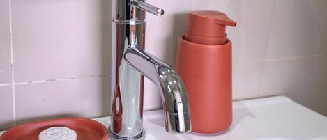 A bathroom with a white sink, chrome faucet, and a red soap dish.