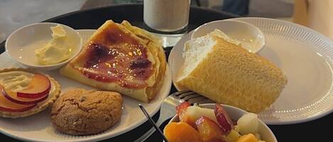 A tray with food items including a pie, cookies, fruit, and a drink.