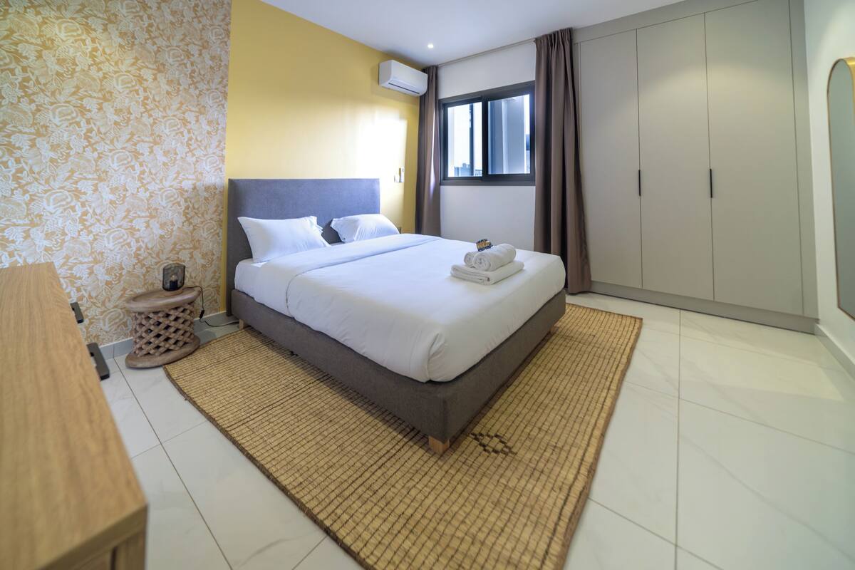 A neatly arranged hotel room with a bed, bedside table, and wardrobe.