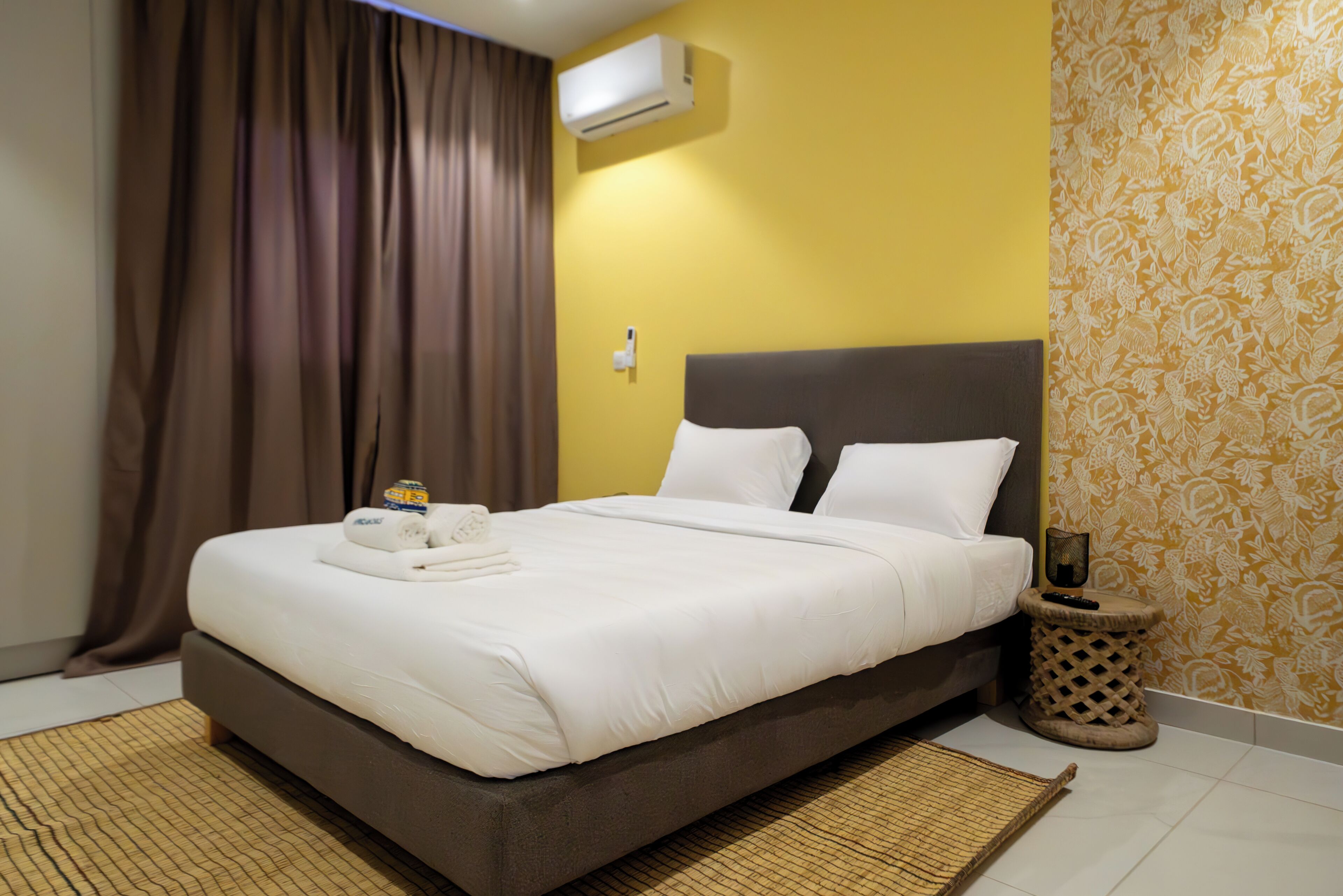 Una camera d'albergo con un letto, un comodino, un climatizzatore e una parete decorata.