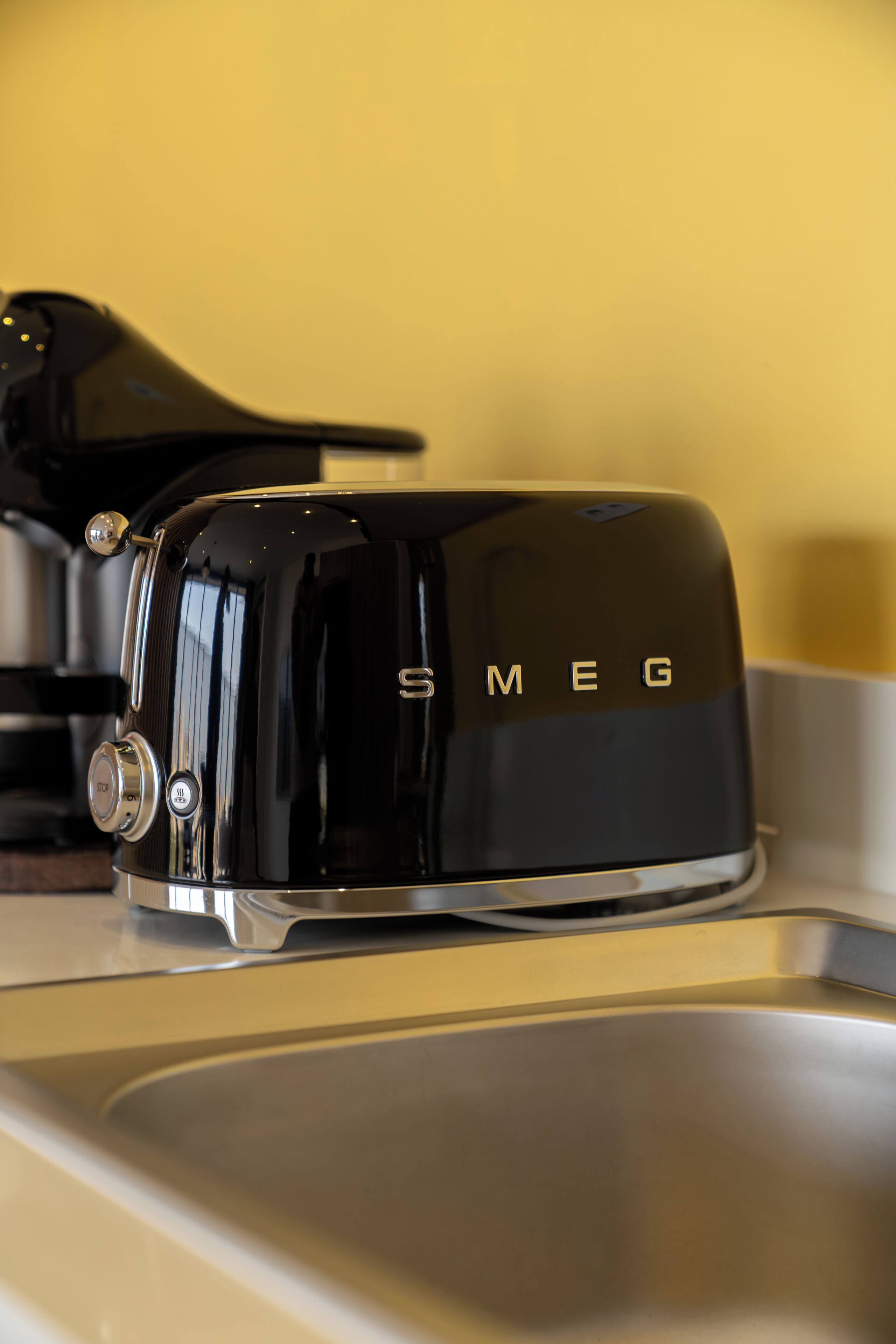 A black toaster with the brand name "SMEG" on a kitchen counter.