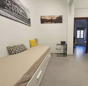 Une chambre à coucher comprenant un lit, une petite table, un radiateur et une porte donnant sur une autre pièce.