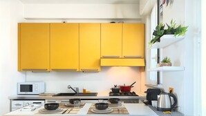 A modern kitchen with yellow cabinets, a microwave, a stove, and a kettle. - Casa Cartesio, steps from San Siro & Ippodromo (Milano)