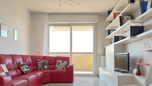 A modern living room with a red leather sofa, a flat-screen TV, and a white chair. - Casa Cartesio, steps from San Siro & Ippodromo (Milano)