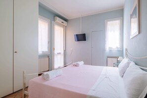 Un dormitorio con una cama, un televisor y una ventana.