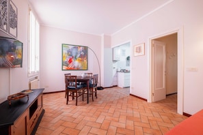 Un comedor con una mesa y sillas, una cocina al fondo y una puerta que da a otra habitación.