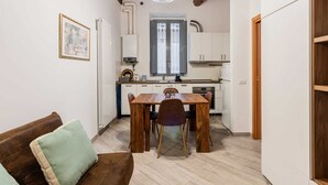 Una cocina compacta con armarios blancos, una mesa de comedor con sillas y techo de madera.