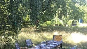 An outdoor dining area with a table and chairs, surrounded by greenery and flowers. - Unter einem Dach (Raabs An Der Thaya)