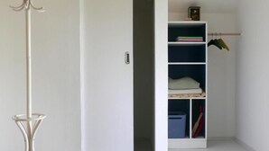 A room with a white wardrobe, a white coat rack, and a shelving unit with clothes and storage bins. - Unter einem Dach (Raabs An Der Thaya)