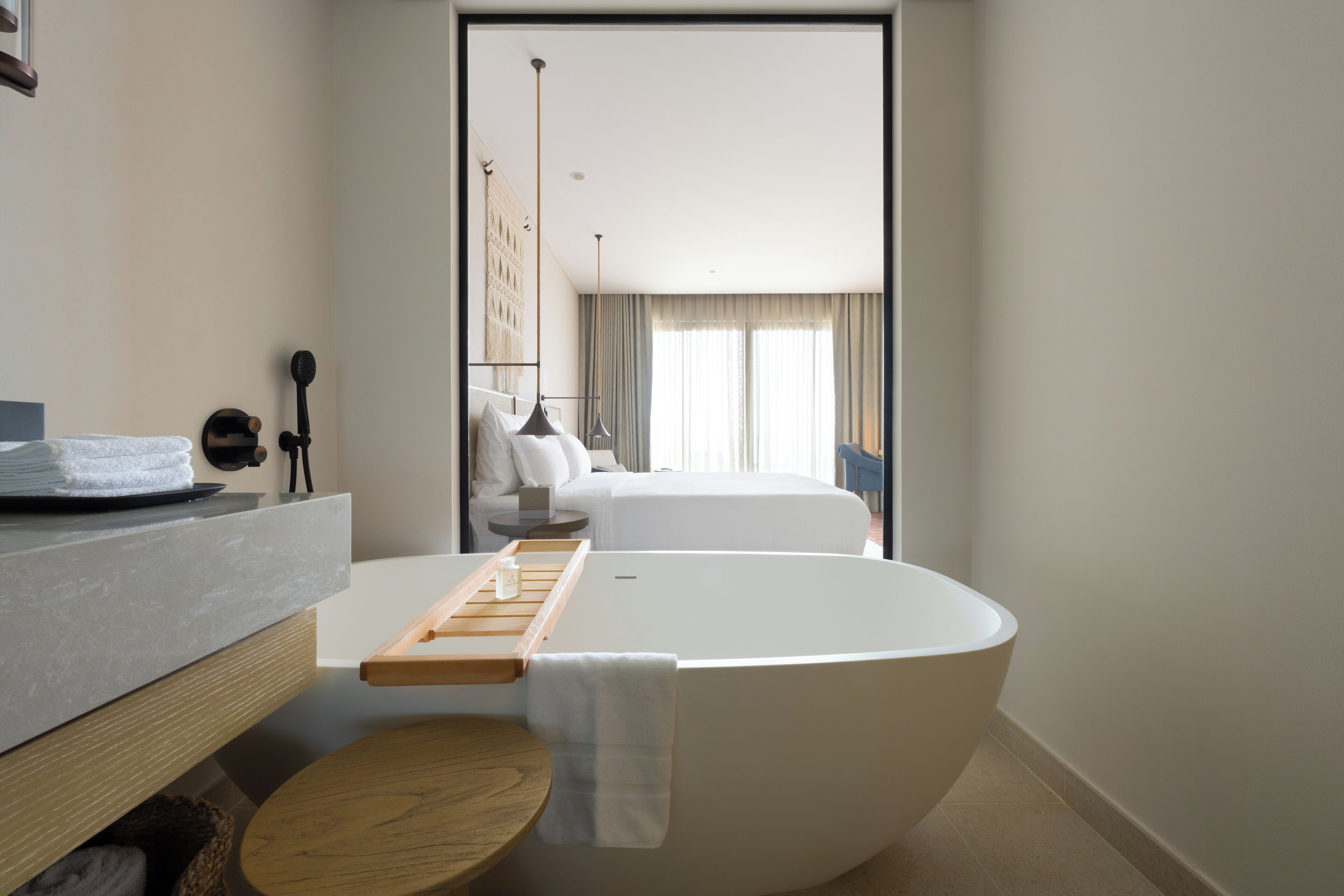 Habitació d'hotel moderna amb una banyera gran, un tocador de fusta i un llit amb vistes a la ciutat.