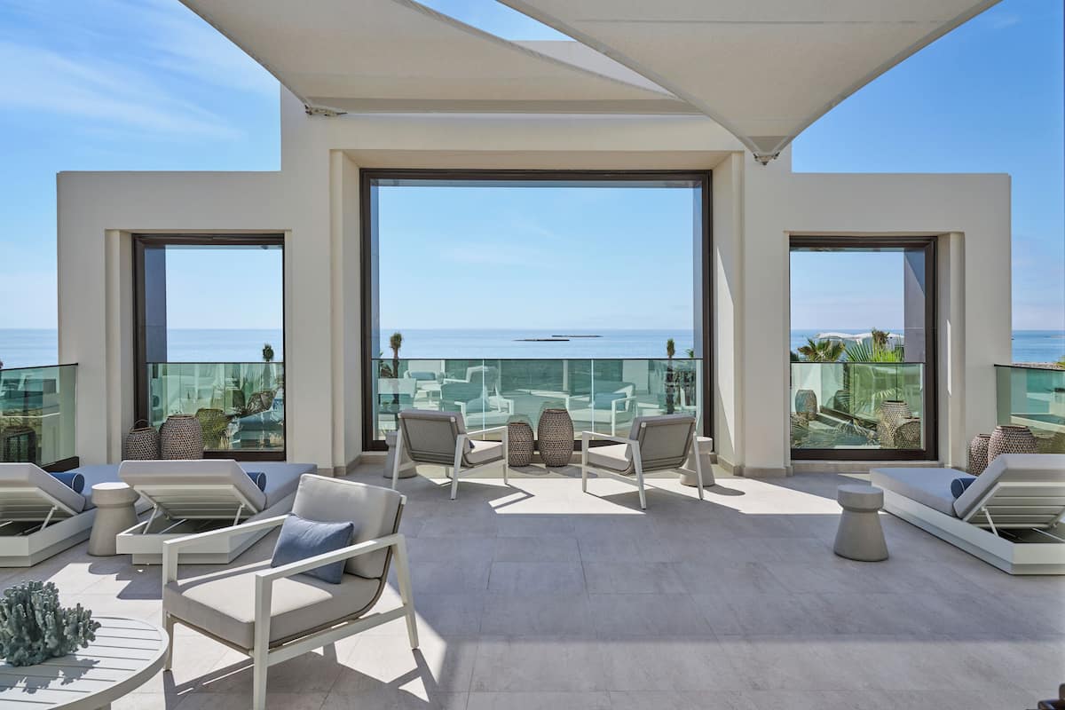 A modern outdoor lounge area with seating and a view of the sea.