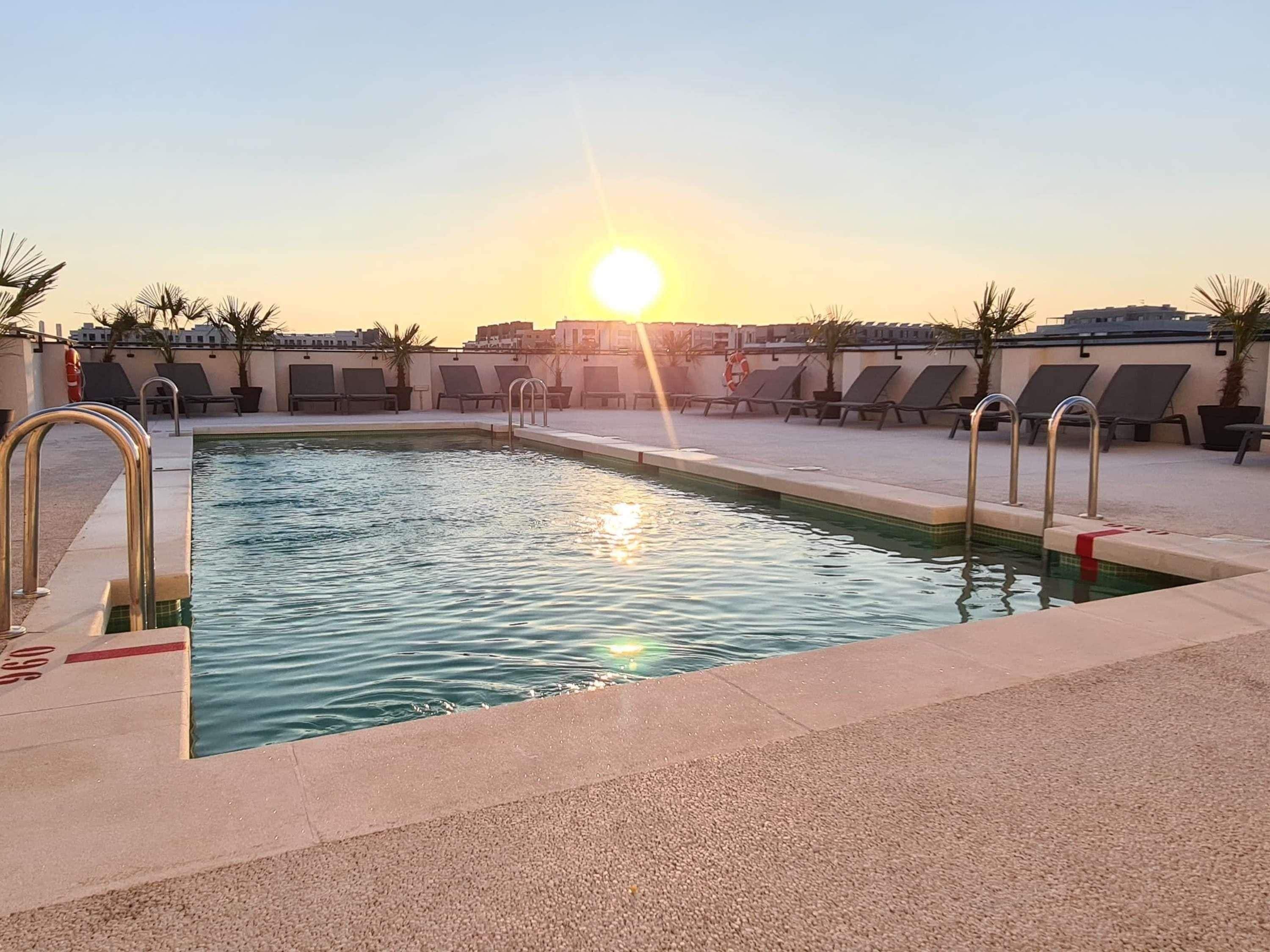 Una piscina con sillas de sol y un puesto de socorristas.