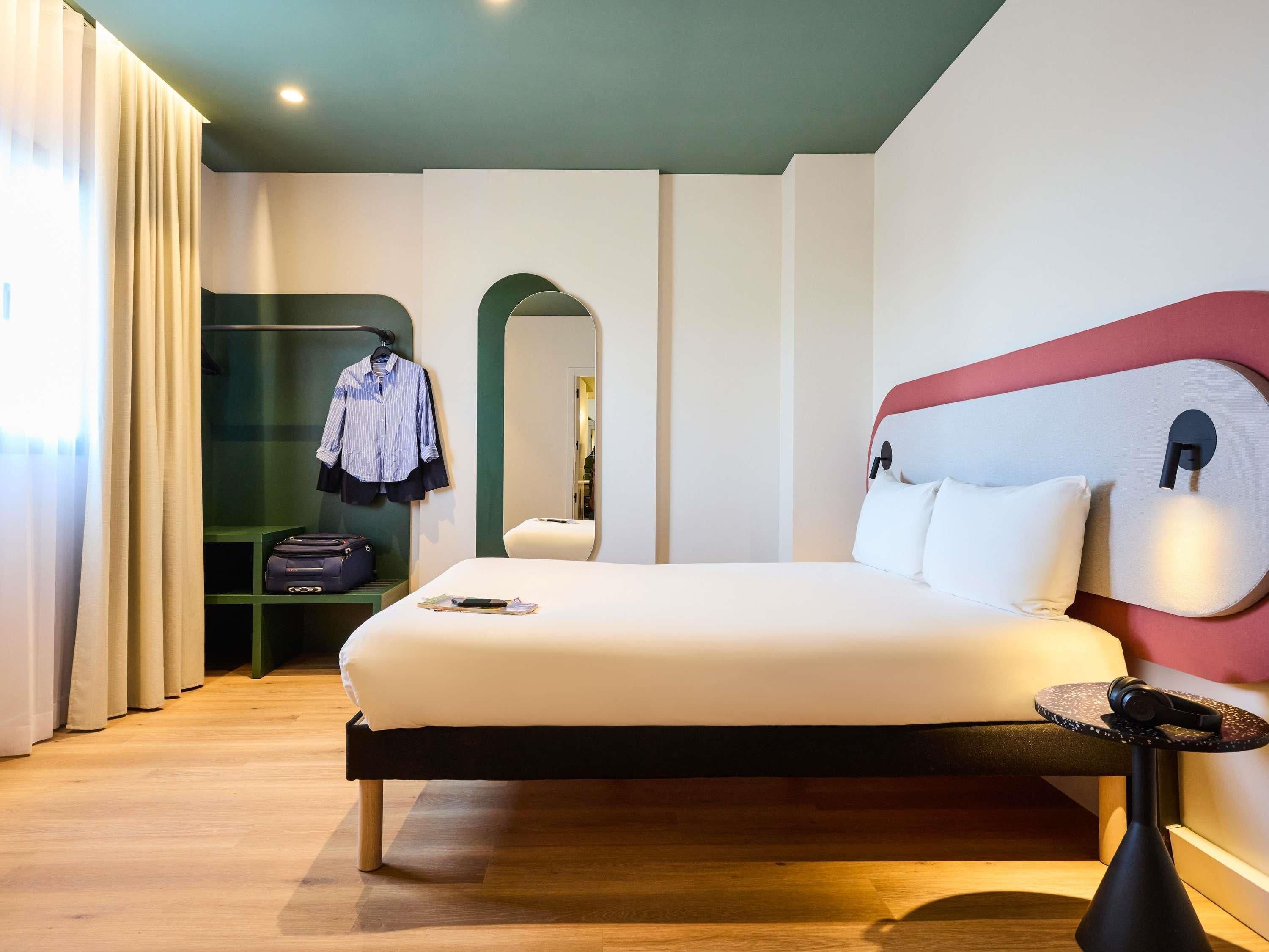 Una habitación de hotel moderna con una cama, un escritorio y un armario.
