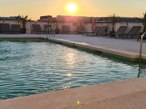 Ein Pool auf dem Dach mit Liegestühlen und einem Rettungsring, umgeben von Gebäuden.
