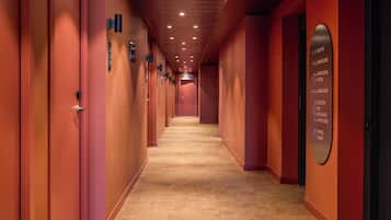 Un pasillo de hotel con puertas indicando diferentes servicios, como restaurante, spa y estacionamiento.