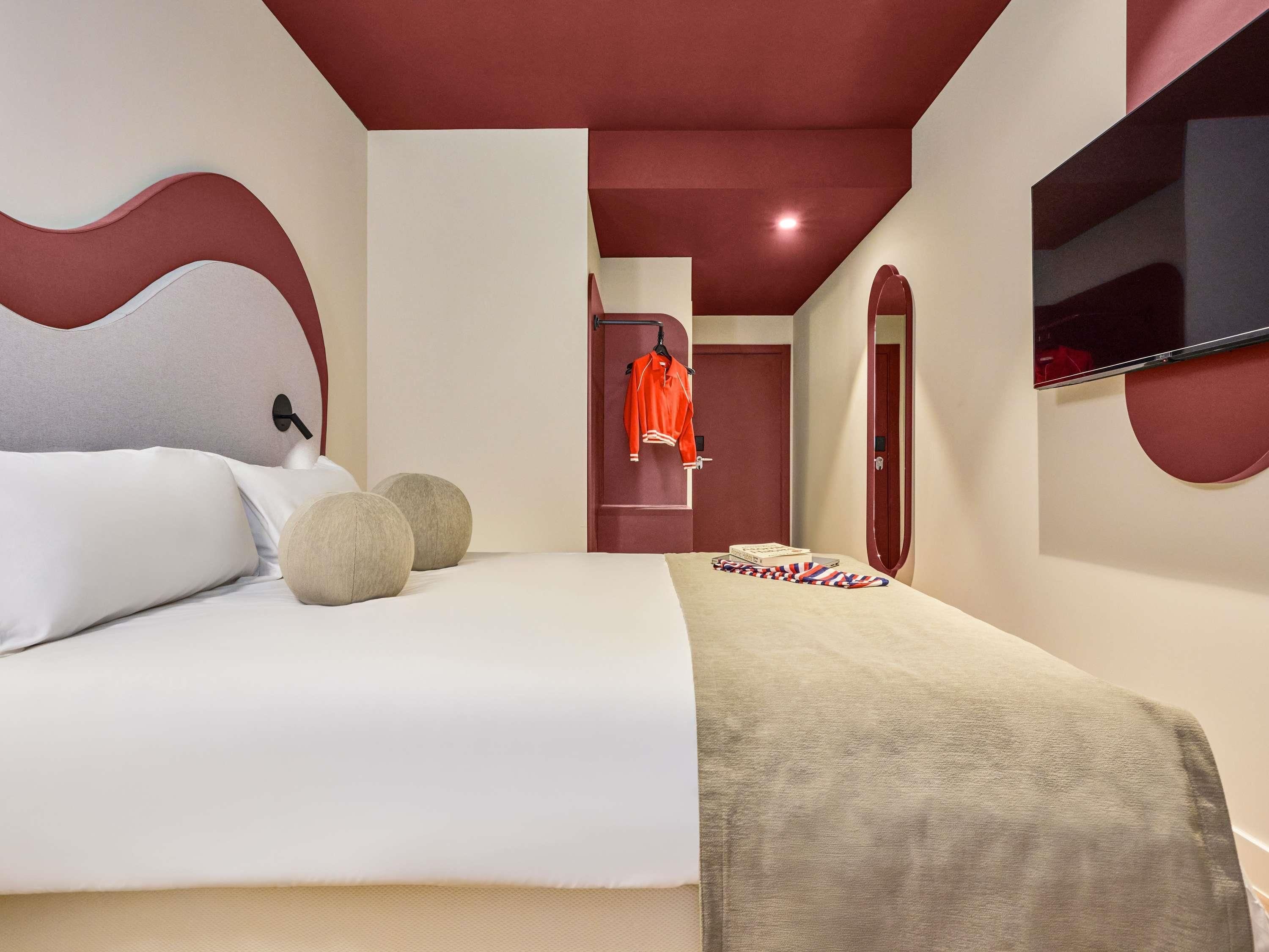 Une chambre d’hôtel avec un lit, une télévision, une armoire et un miroir.