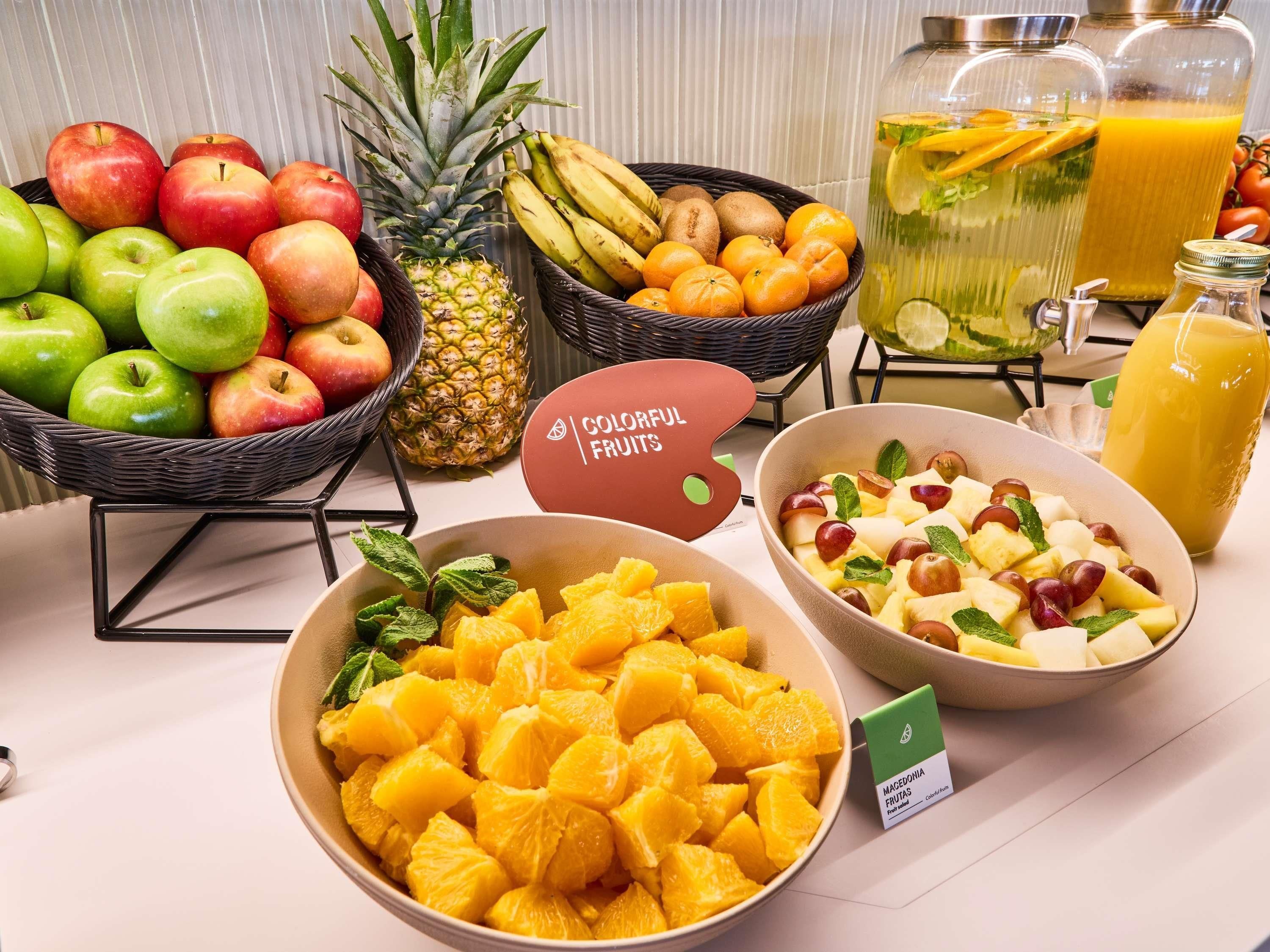 Eine Obstauslage mit Äpfeln, Bananen, Orangen und einer Ananas.