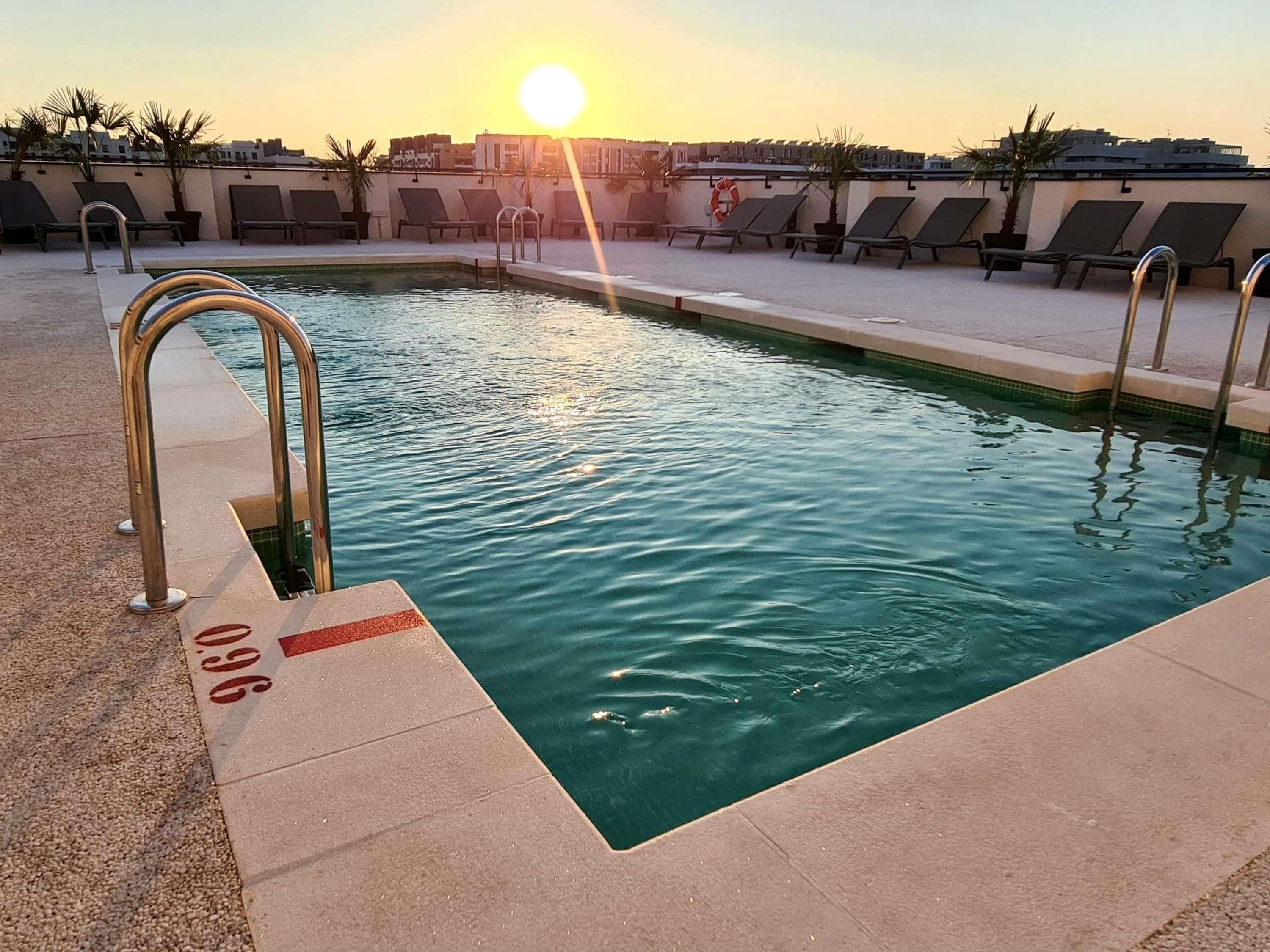 Piscina en la azotea con sillas de sol y un flotador.