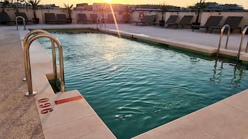 Piscina en la azotea con sillas de sol y un flotador.