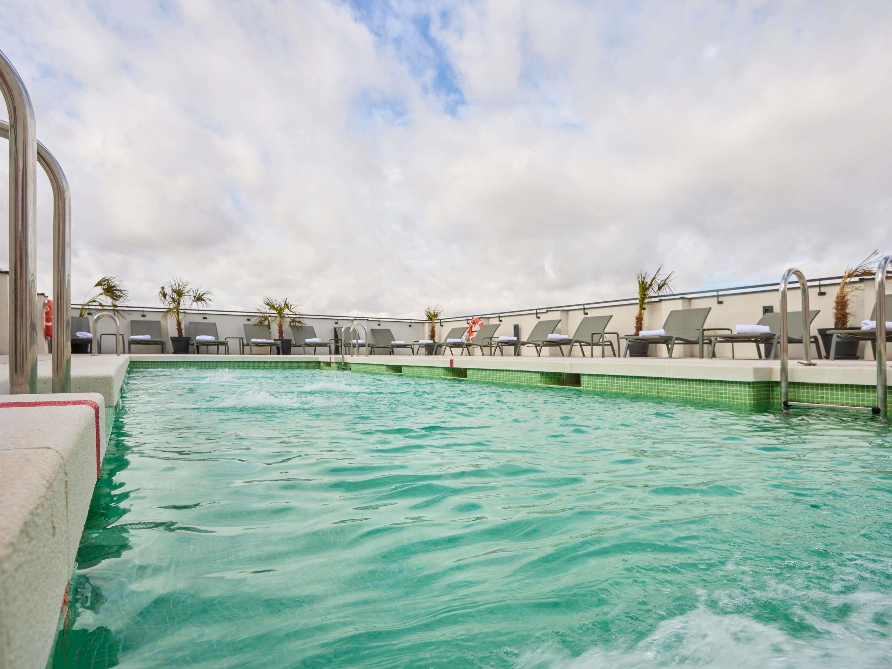 Una piscina con sillones de descanso y palmeras.