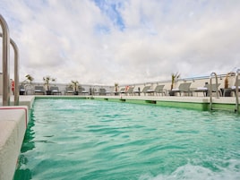 Ein Schwimmbad mit Liegestühlen und Palmen.