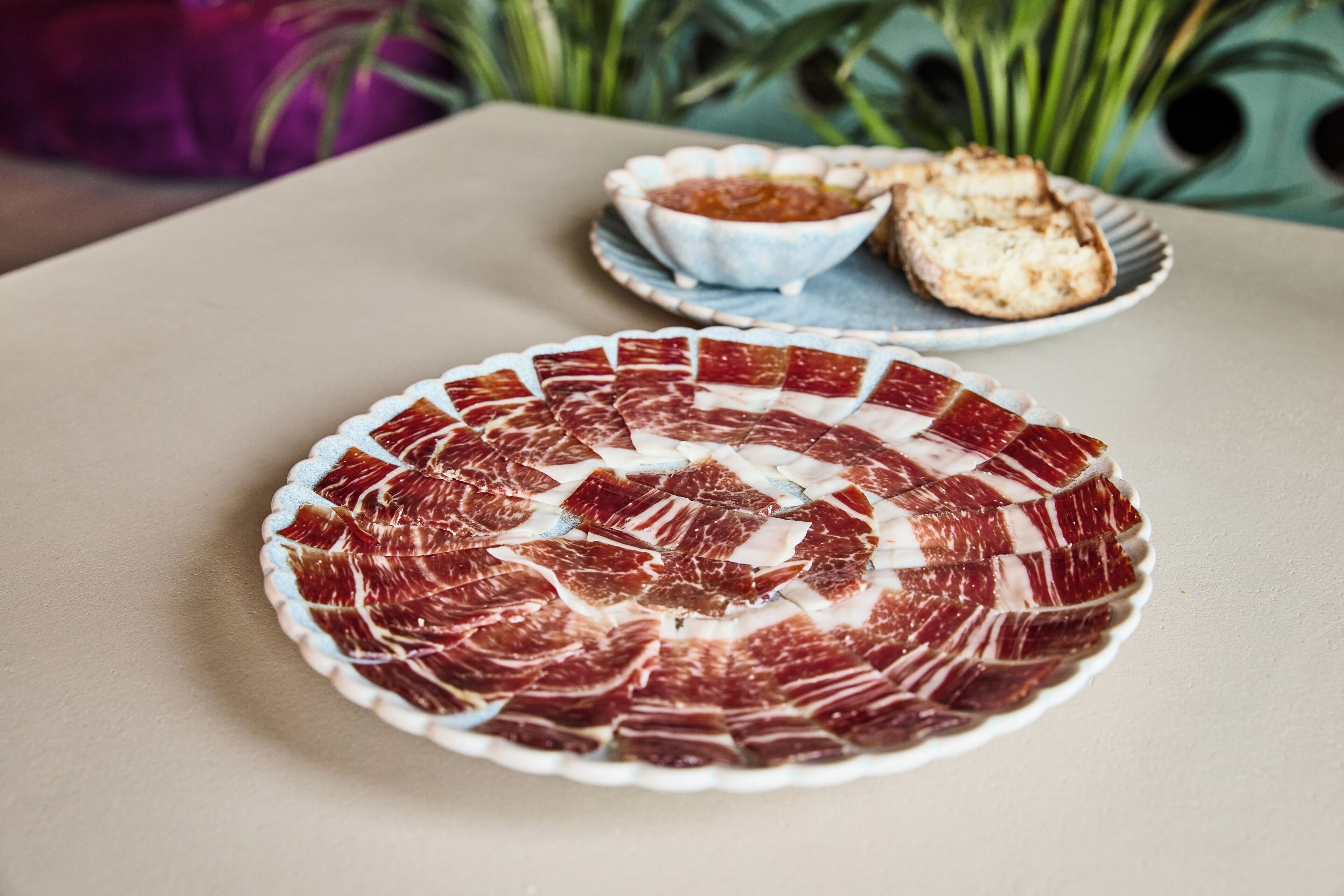 A plate of sliced meat arranged in a circular pattern on a table.