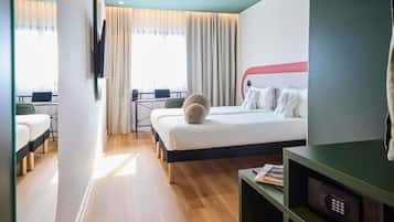 Habitación de hotel con cama, escritorio, silla, televisión y ventana con cortinas.