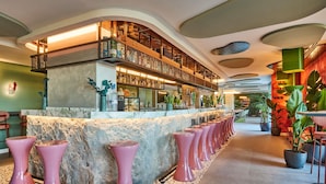 A bar area with a marble counter, pink stools, and a variety of bottles and glasses. - ibis Styles Madrid Airport Valdebebas (Madrid)
